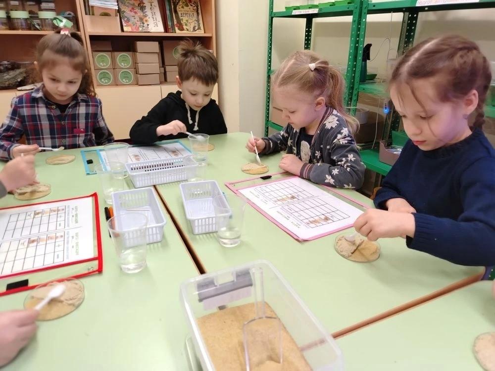 Дети проверяют свойство песка - сыпучесть