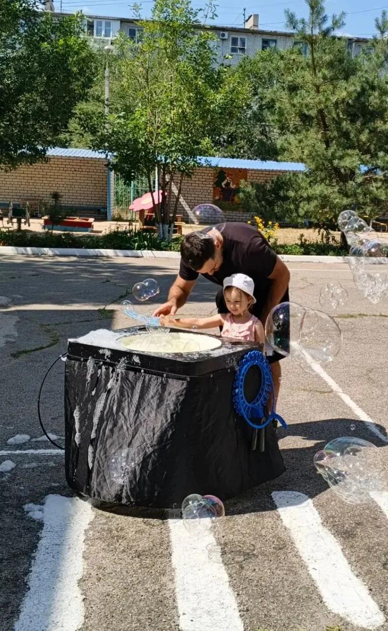 Девочка с аниматором надувают мыльный пузырь